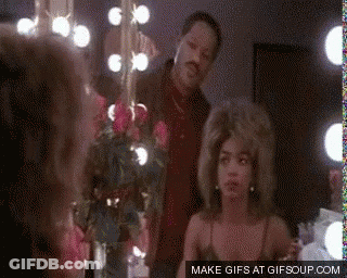 A Man And Woman Are Standing In Front Of A Mirror . GIF
