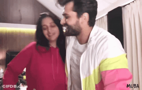A Man And Woman Are Standing Next To Each Other And The Man Is Wearing A Jacket That Says Muba On It GIF