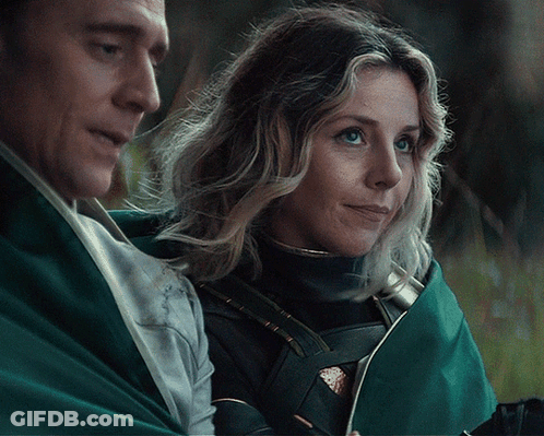 A Man And Woman Are Standing Next To Each Other And The Woman Is Smiling GIF