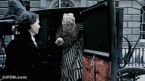 A Man And Woman Are Standing Next To Each Other In A Carriage . GIF