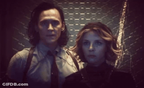 A Man And Woman Are Standing Next To Each Other In A Dark Room . GIF