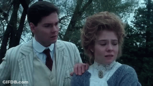 A Man And Woman Are Standing Next To Each Other In A Park . GIF