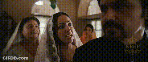 A Man And Woman Are Standing Next To Each Other In A Room . The Woman Is Wearing A Veil . GIF