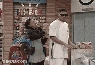 A Man And Woman Are Standing Next To Each Other In A Store . GIF