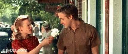 A Man And Woman Are Standing Next To Each Other On A Sidewalk . GIF