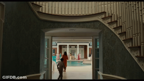 A Man And Woman Are Walking Down A Staircase Towards A Pool GIF