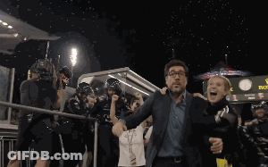 A Man And Woman Are Walking In Front Of A Sign That Says Rolex GIF