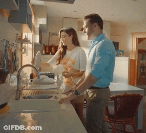 A Man And Woman Are Washing Dishes In A Kitchen Sink GIF