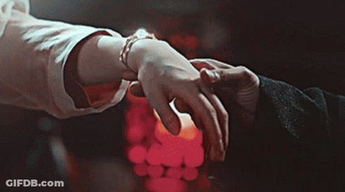 A Man And Woman Holding Hands In Front Of A Candle GIF