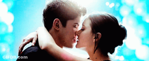 A Man And Woman Kissing In Front Of A Blue Sky GIF