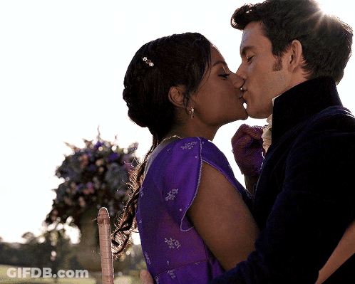 A Man And Woman Kissing In Front Of Flowers GIF