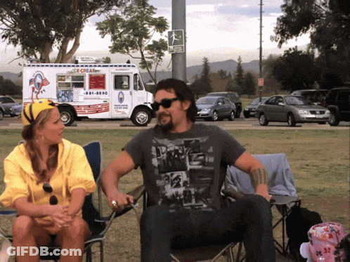 A Man And Woman Sit In Front Of An Ice Cream Truck That Says Ice Cream GIF