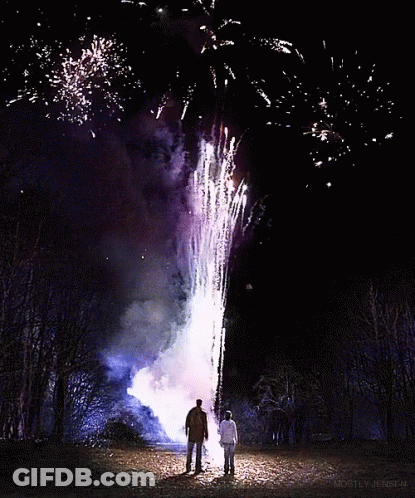 A Man And Woman Standing In Front Of A Fireworks Display That Is Being Displayed By Monty Jensen GIF