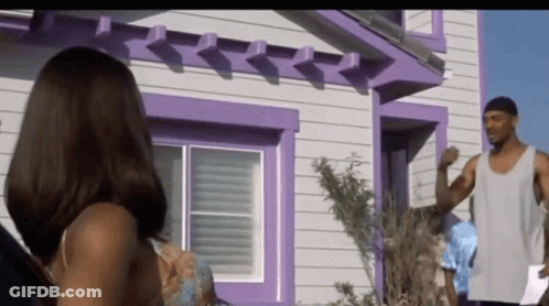 A Man And Woman Standing In Front Of A Purple House GIF