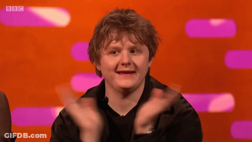 A Man Applauds In Front Of A Screen That Says Bbc On It GIF