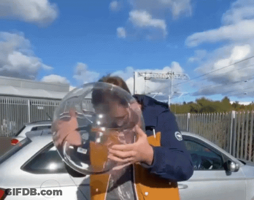 A Man Blowing Up A Balloon In Front Of A Car GIF