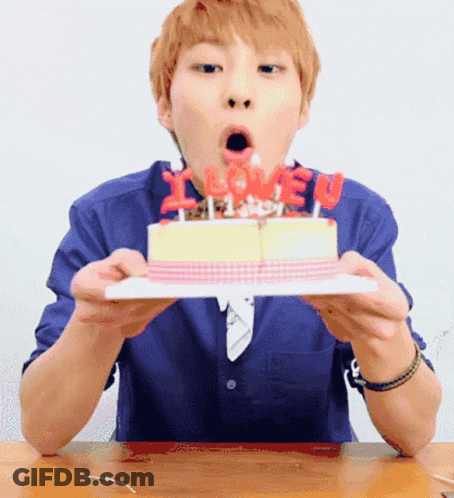 A Man Blows Out Candles On A Birthday Cake That Says I Love You GIF