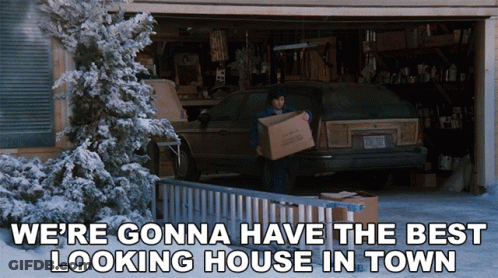 A Man Carrying A Box In Front Of A Garage With The Words We 'Re Gonna Have The Best Looking House In Town GIF