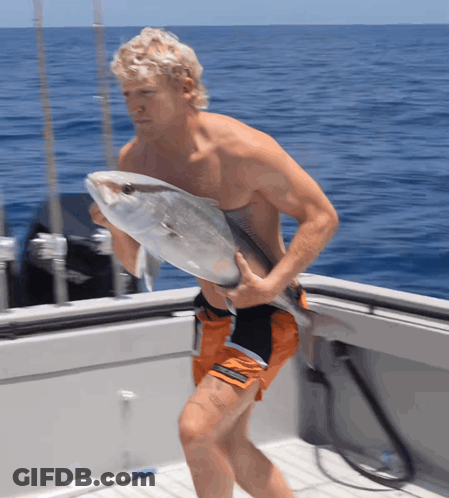 A Man Carrying A Large Fish On A Boat In The Ocean GIF