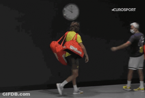 A Man Carrying A Red Wilson Duffel Bag Walks With Another Man GIF