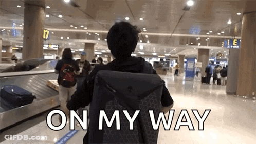 A Man Carrying A Suitcase Walks Through An Airport With The Words " On My Way " Behind Him GIF