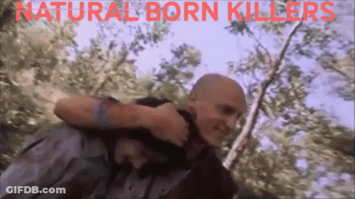 A Man Carrying Another Man With The Words Natural Born Killers Written On The Bottom GIF