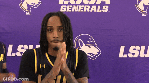 A Man Clapping In Front Of A Purple Banner That Says Lsu GIF