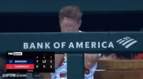 A Man Covering His Face In Front Of A Bank Of America Banner GIF