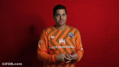 A Man Covering His Face While Holding A Card That Says Kaiser Permanent GIF