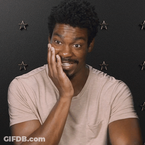 A Man Covering His Face With His Hand In Front Of A Black Background With Stars GIF
