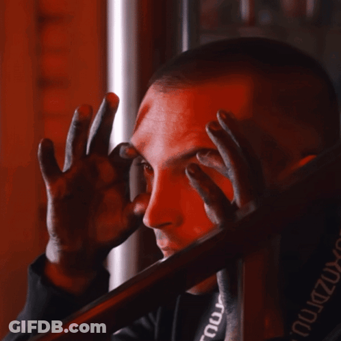 A Man Covering His Face With His Hands And A Black Shirt With The Word Tour On The Back GIF