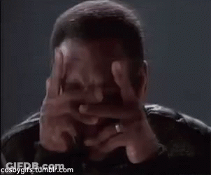 A Man Covering His Face With His Hands In A Dark Room . GIF