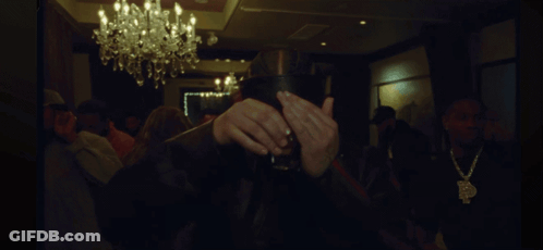 A Man Covering His Face With His Hands In A Dark Room With A Chandelier GIF