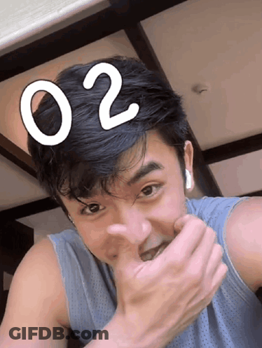 A Man Covering His Mouth With His Hand And The Number 02 On His Head GIF