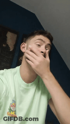 A Man Covering His Mouth With His Hand And Wearing A Green Shirt That Says " Jaioio " GIF