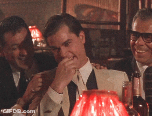 A Man Covering His Mouth With His Hand While Sitting At A Table GIF