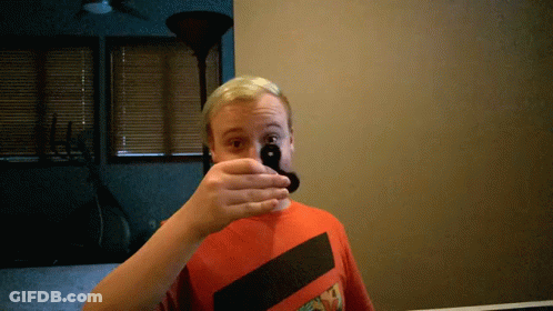 A Man Covering His Mouth With His Hand While Wearing A Red Shirt GIF