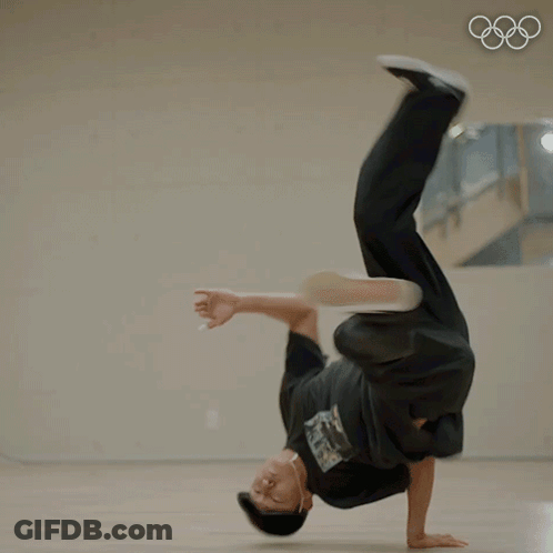A Man Doing A Handstand In Front Of A Mirror With The Olympic Rings In The Background GIF