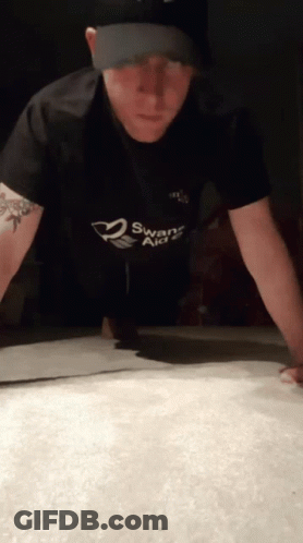 A Man Doing Push Ups With A Swans Aid Shirt On GIF
