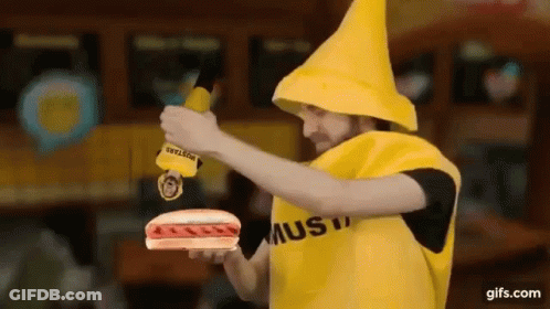 A Man Dressed As A Banana Is Holding A Hot Dog And Mustard . GIF