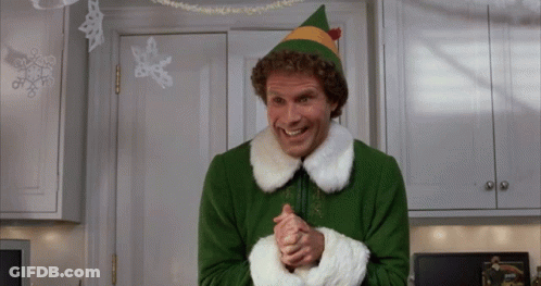 A Man Dressed As A Christmas Elf Is Smiling In A Kitchen GIF