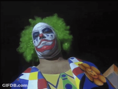 A Man Dressed As A Clown With A Teddy Bear Pinned To His Chest GIF