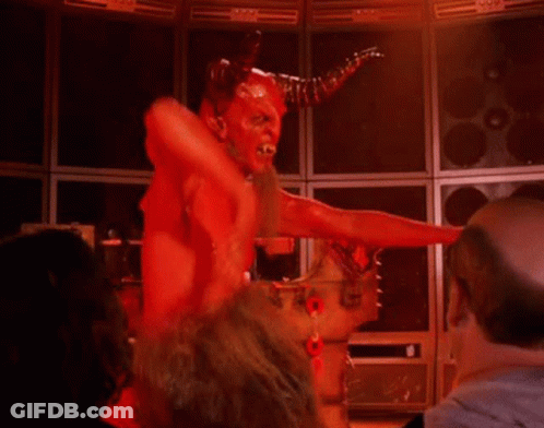 A Man Dressed As A Devil With Horns Is Standing In A Room . GIF