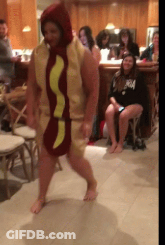 A Man Dressed As A Hot Dog Is Dancing In Front Of A Crowd GIF