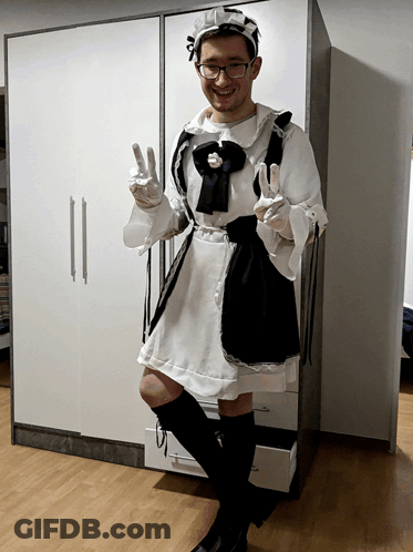 A Man Dressed As A Maid Giving A Peace Sign GIF
