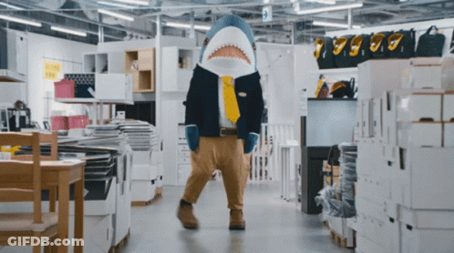 A Man Dressed As A Shark In A Store GIF