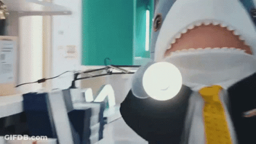 A Man Dressed As A Shark Is Holding A Flashlight GIF