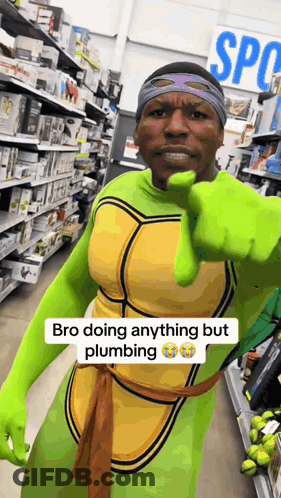 A Man Dressed As A Teenage Mutant Ninja Turtle Is Pointing At The Camera GIF