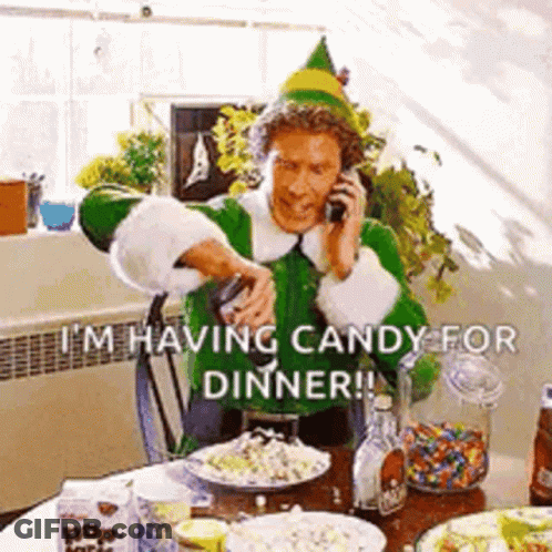 A Man Dressed As An Elf Is Talking On A Cell Phone While Sitting At A Table . GIF