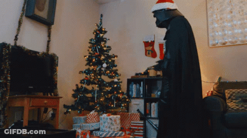 A Man Dressed As Darth Vader Standing In Front Of A Christmas Tree GIF